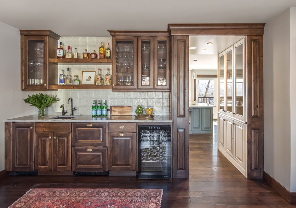 Photo of a mid-sized transitional single-wall wet bar in Denver with raised-panel cabinets, dark wood cabinets, quartzite benchtops, dark hardwood floors, an undermount sink, porcelain splashback and brown floor.