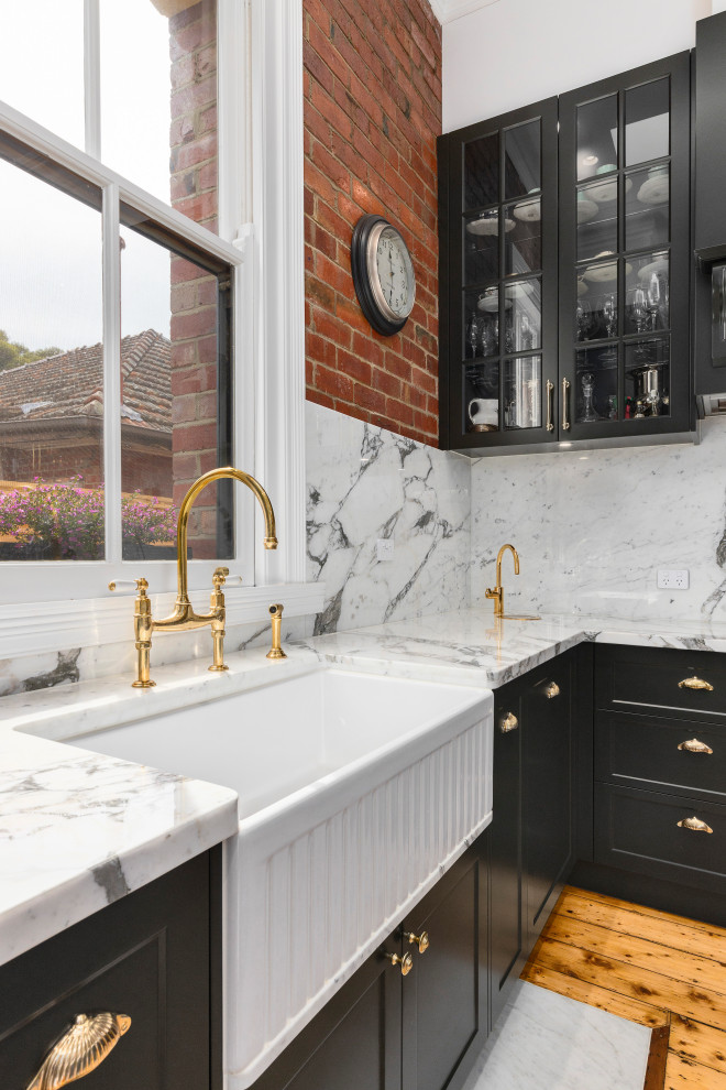 Inspiration for a large traditional l-shaped separate kitchen in Melbourne with a farmhouse sink, recessed-panel cabinets, black cabinets, marble benchtops, marble splashback, black appliances, light hardwood floors and with island.