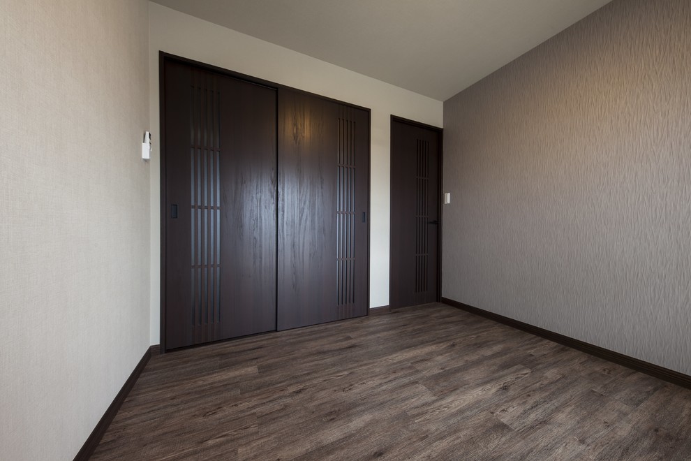 Imagen de dormitorio principal y gris de estilo zen de tamaño medio con paredes grises, suelo marrón, papel pintado y papel pintado