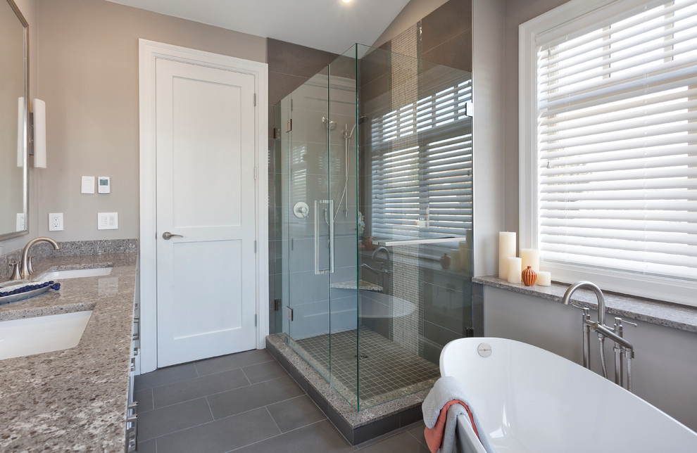 Photo of a mid-sized transitional master bathroom in Vancouver with an undermount sink, shaker cabinets, white cabinets, granite benchtops, a freestanding tub, a corner shower, a two-piece toilet, gray tile, ceramic tile, grey walls and ceramic floors.