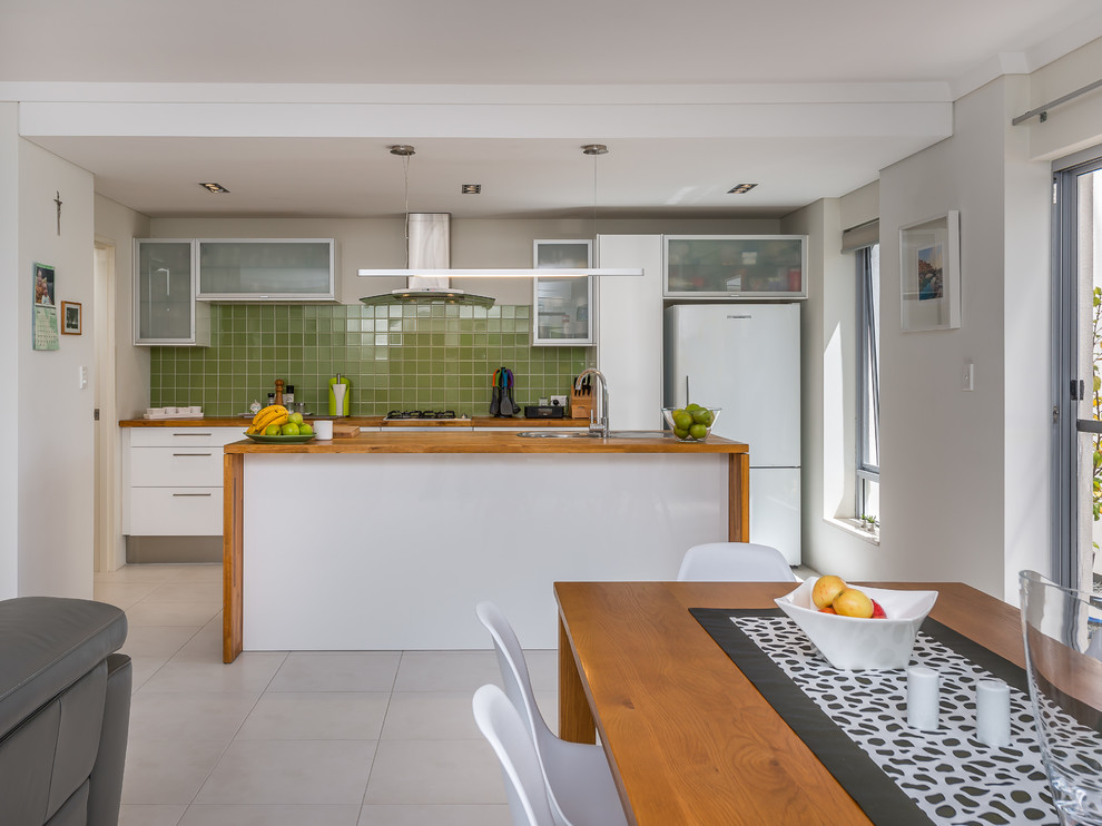 This is an example of a mid-sized contemporary galley open plan kitchen in Perth with a double-bowl sink, flat-panel cabinets, white cabinets, wood benchtops, green splashback, ceramic splashback, stainless steel appliances, porcelain floors and with island.