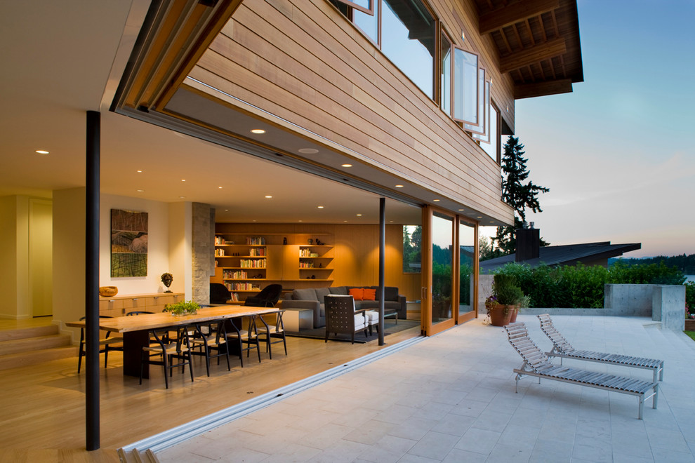 This is an example of a large contemporary backyard patio in Seattle with natural stone pavers and a roof extension.