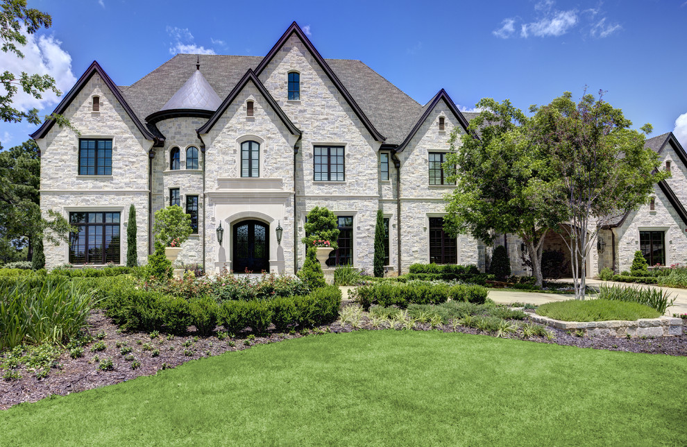 This is an example of a traditional two-storey exterior in Dallas with stone veneer and a gable roof.