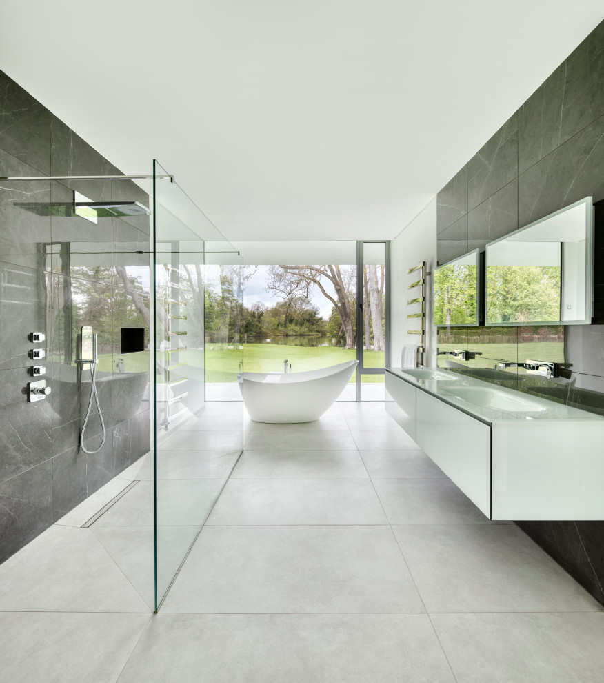 Large modern bathroom in Oxfordshire with flat-panel cabinets, white cabinets, a freestanding tub, a curbless shower, gray tile, an integrated sink, grey floor, an open shower, white benchtops, a niche, a double vanity and a floating vanity.
