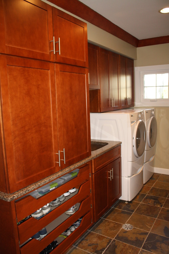 This is an example of a mid-sized traditional galley utility room in Detroit with an undermount sink, recessed-panel cabinets, medium wood cabinets, granite benchtops, beige walls, slate floors and a side-by-side washer and dryer.