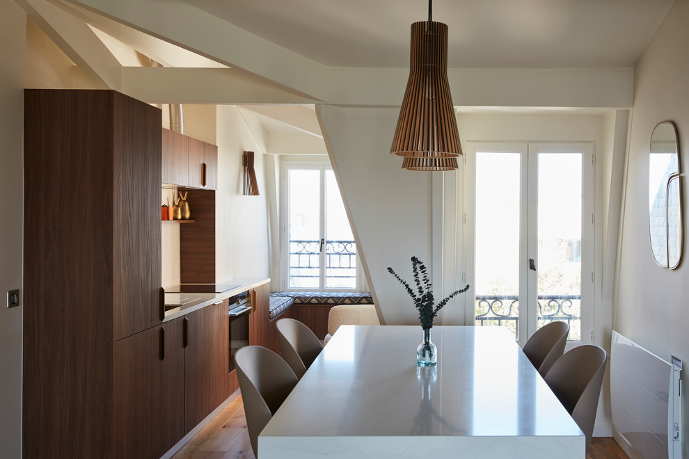 Foto på ett funkis vit linjärt kök och matrum, med en undermonterad diskho, släta luckor, skåp i mellenmörkt trä, bänkskiva i kvarts, vitt stänkskydd, integrerade vitvaror, mellanmörkt trägolv och brunt golv