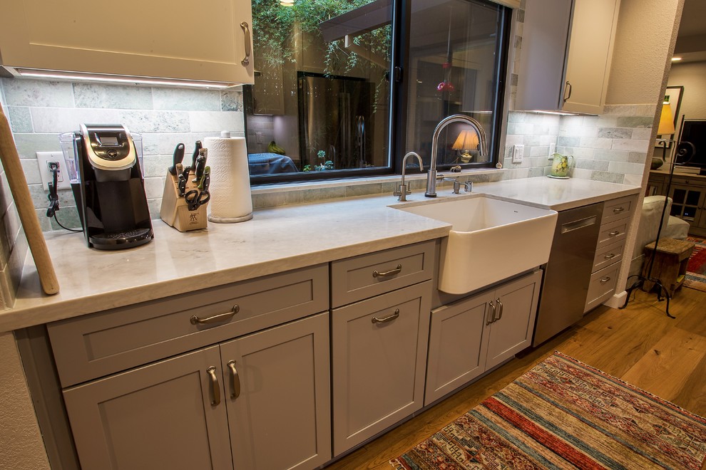 Inspiration for a large transitional galley light wood floor and brown floor open concept kitchen remodel in Sacramento with a farmhouse sink, shaker cabinets, gray cabinets, quartz countertops, gray backsplash, stone tile backsplash, stainless steel appliances, no island and white countertops