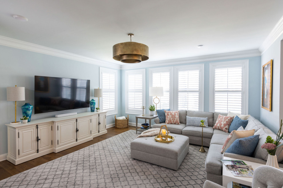 Modelo de sala de estar clásica renovada grande con paredes azules, suelo laminado, marco de chimenea de piedra y suelo marrón
