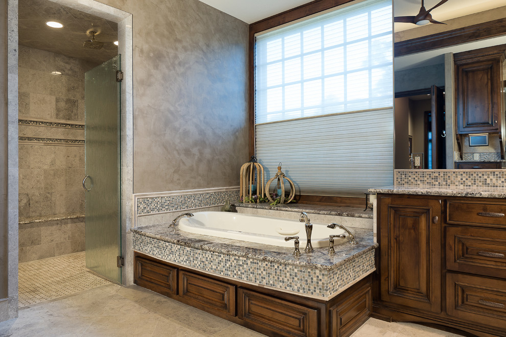 Inspiration for a large transitional master bathroom in Kansas City with raised-panel cabinets, dark wood cabinets, a drop-in tub, a double shower, a bidet, multi-coloured tile, mosaic tile, grey walls, travertine floors, a drop-in sink and granite benchtops.