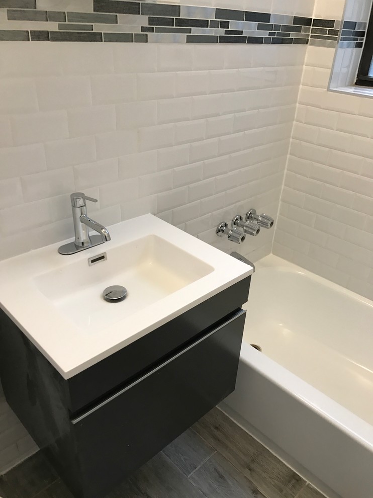 This is an example of a small contemporary 3/4 bathroom in New York with flat-panel cabinets, black cabinets, an alcove tub, a shower/bathtub combo, beige tile, brown tile, gray tile, subway tile, dark hardwood floors, a wall-mount sink and engineered quartz benchtops.