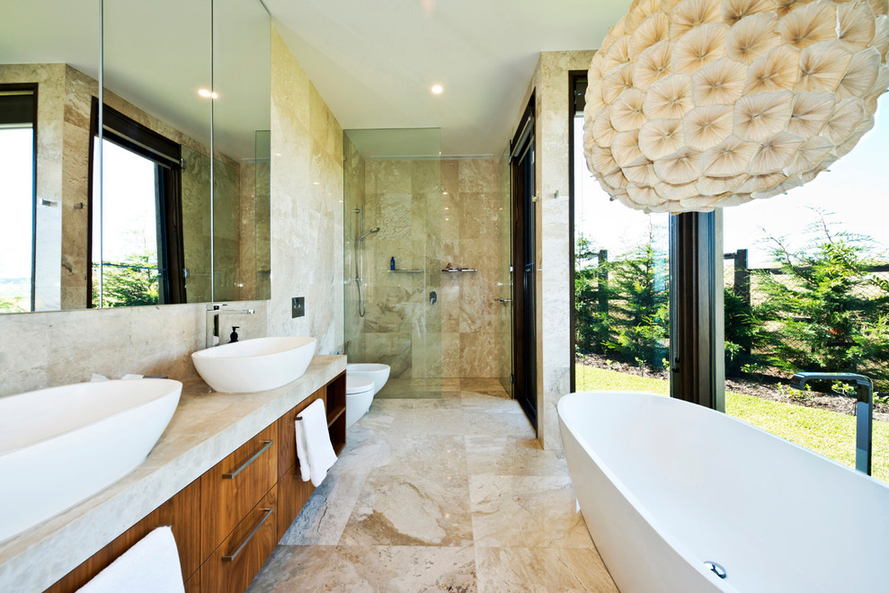 Large contemporary master bathroom in Melbourne with medium wood cabinets, a freestanding tub, an open shower, a two-piece toilet, beige tile, marble, beige walls, marble floors, a vessel sink, marble benchtops, beige floor, an open shower and beige benchtops.