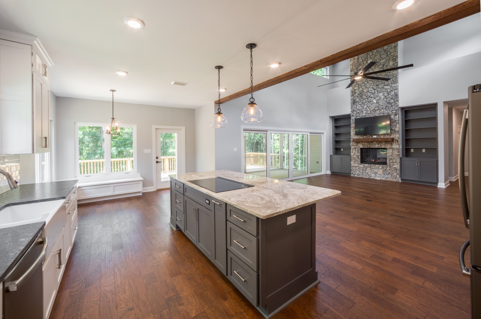 Inspiration for a mid-sized timeless galley medium tone wood floor and brown floor eat-in kitchen remodel with a farmhouse sink, recessed-panel cabinets, white cabinets, quartzite countertops, white backsplash, glass tile backsplash, stainless steel appliances, an island and multicolored countertops