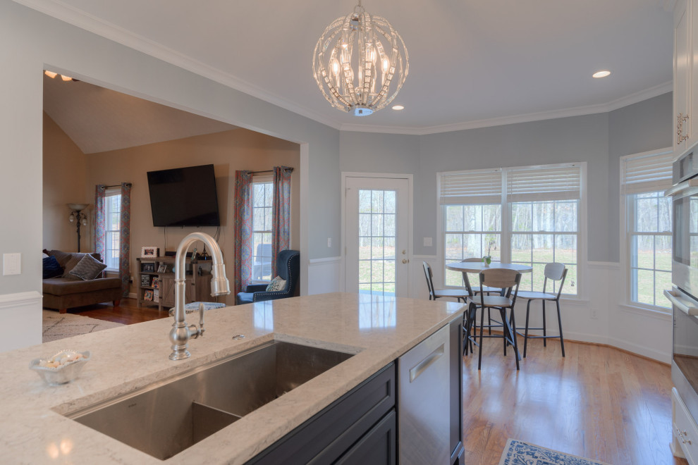 Inspiration for a mid-sized transitional galley medium tone wood floor eat-in kitchen remodel with an undermount sink, flat-panel cabinets, white cabinets, quartz countertops, white backsplash, subway tile backsplash, stainless steel appliances, an island and white countertops
