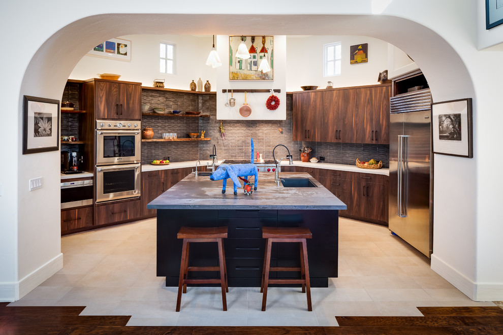 Mid-sized eclectic u-shaped kitchen in San Diego with an undermount sink, flat-panel cabinets, dark wood cabinets, solid surface benchtops, ceramic splashback, stainless steel appliances, porcelain floors, with island, beige floor, grey splashback and white benchtop.
