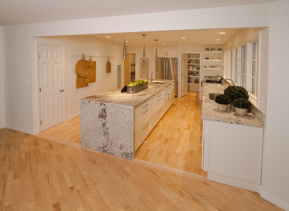 Mid-sized transitional l-shaped light wood floor open concept kitchen photo in Boise with an undermount sink, shaker cabinets, white cabinets, granite countertops, stainless steel appliances and an island