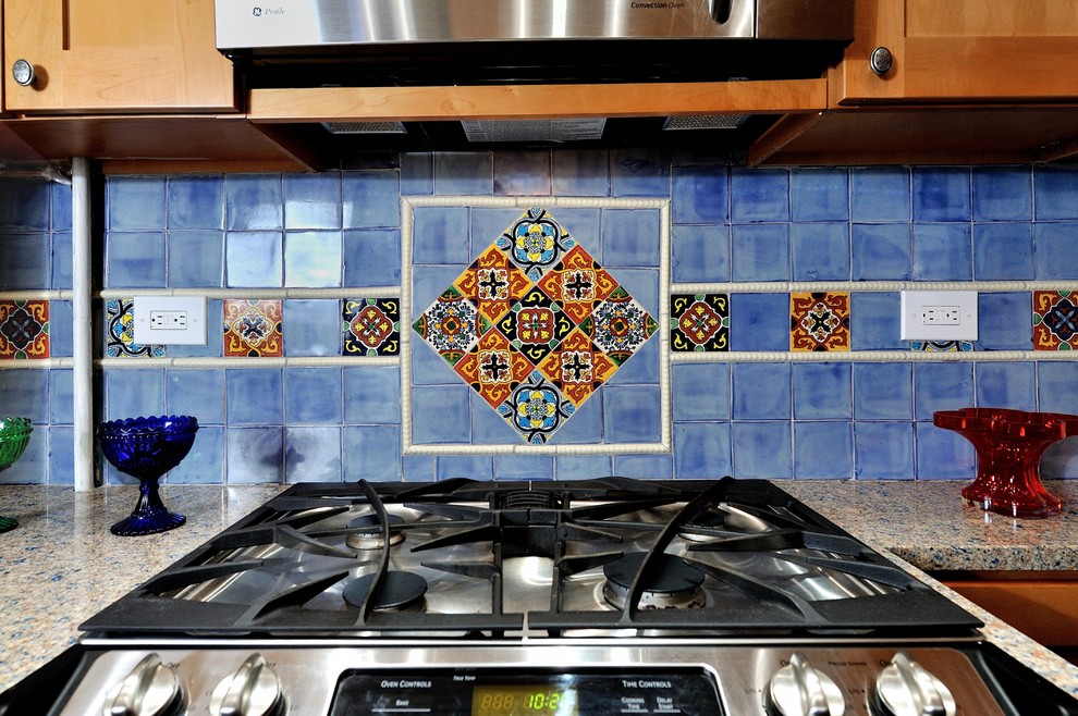 This is an example of a small mediterranean u-shaped separate kitchen in New York with raised-panel cabinets, light wood cabinets, blue splashback, ceramic splashback, stainless steel appliances, recycled glass benchtops, porcelain floors and an undermount sink.