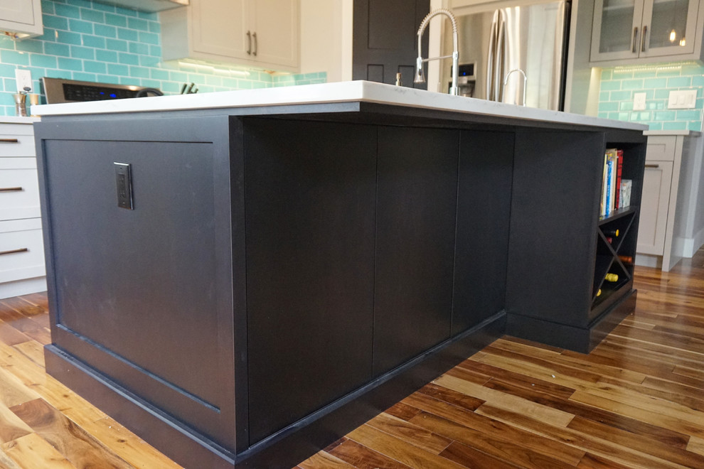 Mid-sized transitional l-shaped medium tone wood floor and brown floor kitchen photo in Calgary with an undermount sink, shaker cabinets, gray cabinets, quartz countertops, blue backsplash, ceramic backsplash, stainless steel appliances and an island
