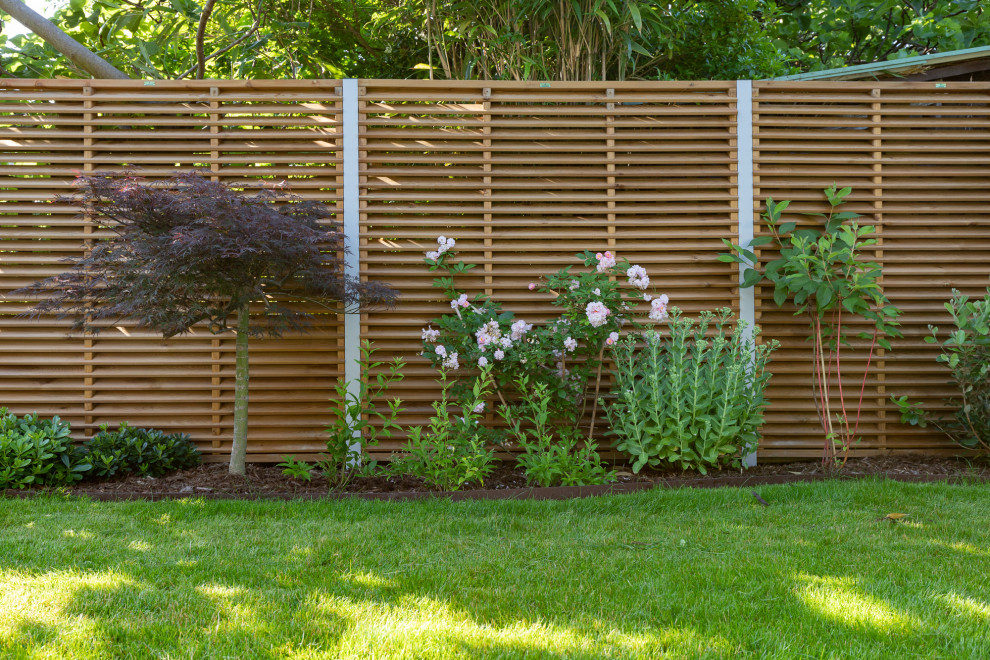 Aménagement d'un jardin arrière classique de taille moyenne et l'été avec une exposition partiellement ombragée et une clôture en bois.