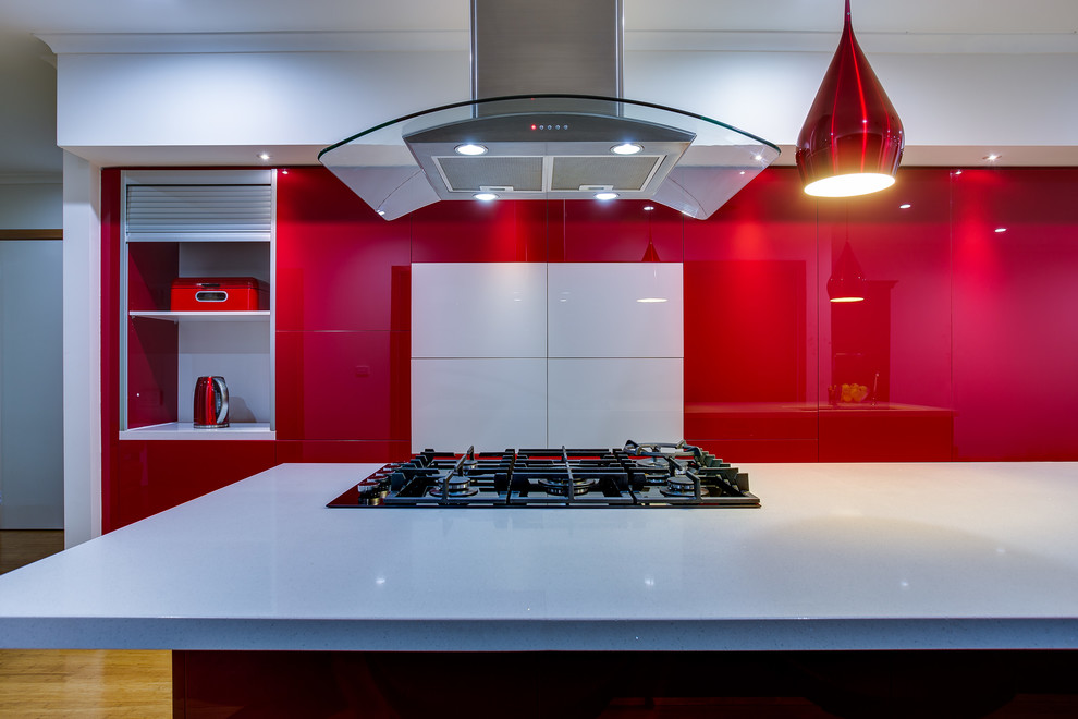 Inspiration for a modern galley open plan kitchen in Melbourne with a double-bowl sink, open cabinets, red cabinets, solid surface benchtops, stainless steel appliances, light hardwood floors and with island.