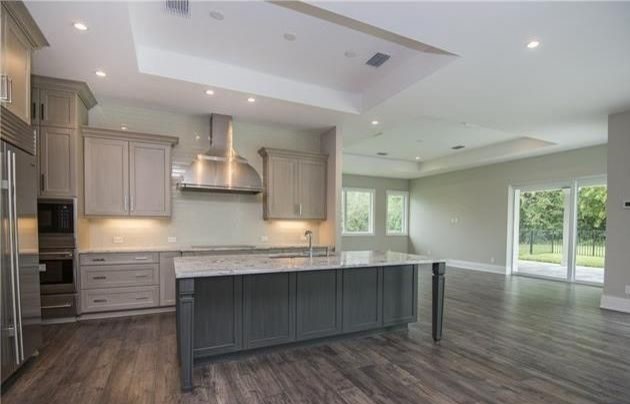 This is an example of a large transitional l-shaped eat-in kitchen in Miami with a single-bowl sink, shaker cabinets, grey cabinets, granite benchtops, beige splashback, glass tile splashback, stainless steel appliances, dark hardwood floors and with island.