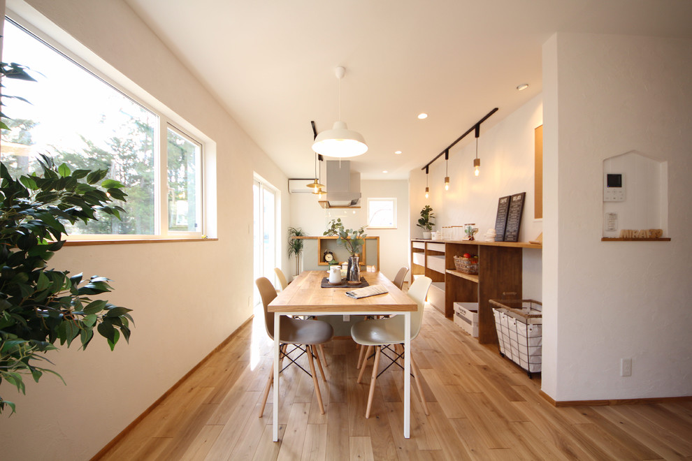 Scandinavian dining room in Other with white walls, medium hardwood floors and brown floor.