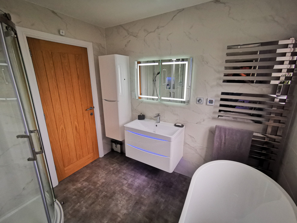 This is an example of a mid-sized contemporary kids bathroom in West Midlands with flat-panel cabinets, white cabinets, a freestanding tub, a corner shower, a wall-mount toilet, black and white tile, marble, white walls, vinyl floors, a wall-mount sink, grey floor, a sliding shower screen, white benchtops, a niche, a single vanity and a floating vanity.