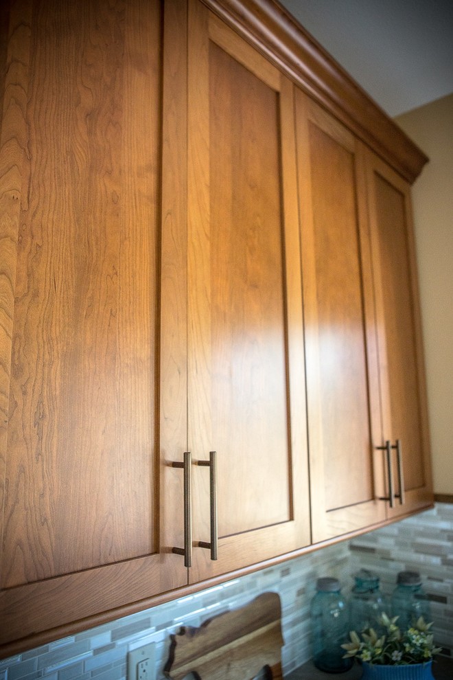 Eat-in kitchen - large transitional l-shaped light wood floor eat-in kitchen idea in Cedar Rapids with a double-bowl sink, recessed-panel cabinets, medium tone wood cabinets, laminate countertops, multicolored backsplash, mosaic tile backsplash, white appliances and an island