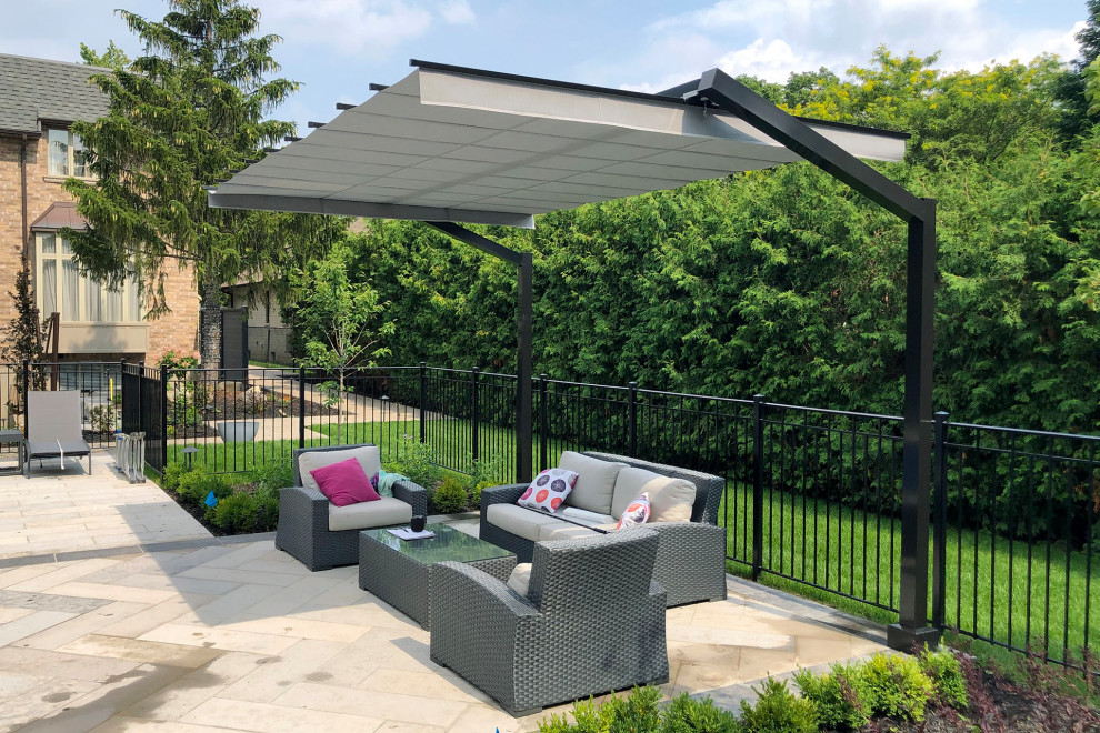 Inspiration for a contemporary back patio in Toronto with natural stone paving and an awning.