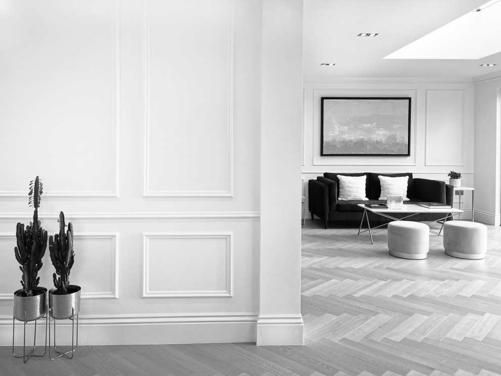Modelo de salón para visitas abierto minimalista de tamaño medio con paredes blancas, suelo de madera clara y panelado