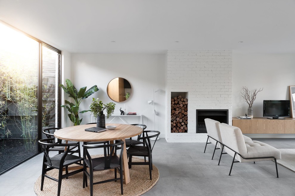 Photo of a contemporary open plan dining in Melbourne with white walls, a ribbon fireplace, a brick fireplace surround and grey floor.