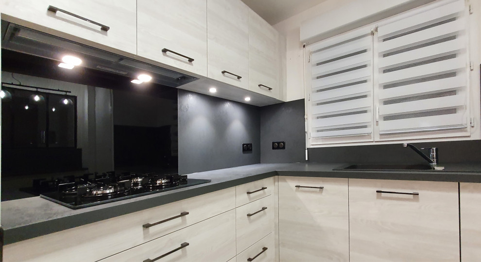 Inspiration for a mid-sized contemporary l-shaped open plan kitchen in Other with an undermount sink, flat-panel cabinets, stainless steel cabinets, granite benchtops, grey splashback, granite splashback, panelled appliances, cement tiles, with island, white floor and black benchtop.