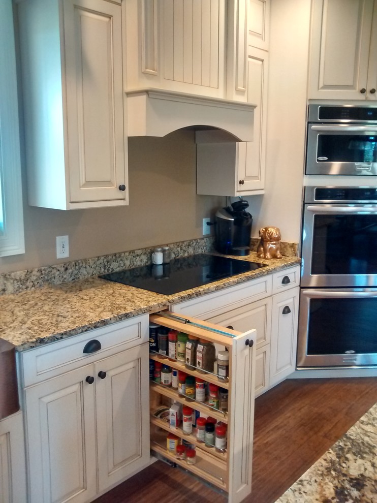 Inspiration for a large transitional l-shaped dark wood floor open concept kitchen remodel in Cincinnati with a farmhouse sink, raised-panel cabinets, distressed cabinets, granite countertops, multicolored backsplash, stone slab backsplash, stainless steel appliances and an island