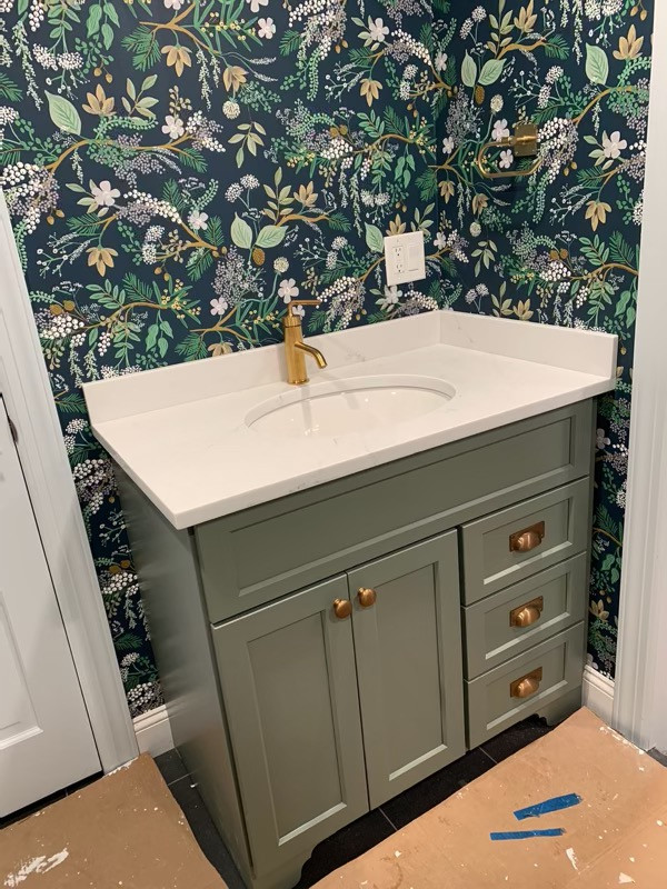 This is an example of a small country 3/4 bathroom in New York with shaker cabinets, green cabinets, a corner shower, a two-piece toilet, multi-coloured tile, multi-coloured walls, ceramic floors, an undermount sink, engineered quartz benchtops, black floor, a hinged shower door, white benchtops, a single vanity, a freestanding vanity and wallpaper.