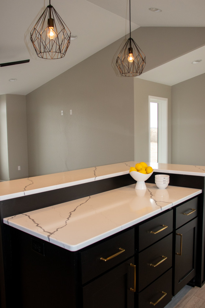 This is an example of a mid-sized modern u-shaped eat-in kitchen in Other with an undermount sink, recessed-panel cabinets, black cabinets, quartz benchtops, stainless steel appliances, vinyl floors, with island, beige floor and white benchtop.