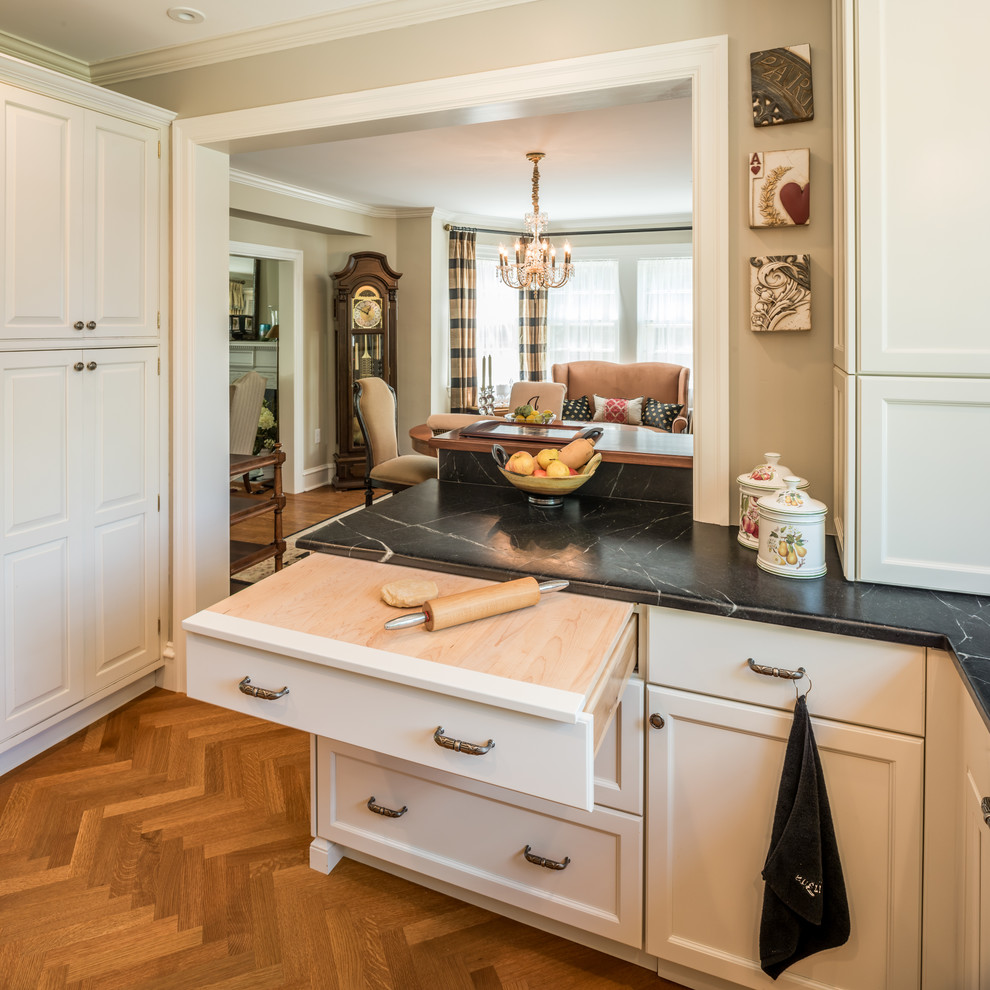 Inspiration for a small traditional u-shaped eat-in kitchen in Philadelphia with an undermount sink, recessed-panel cabinets, grey cabinets, soapstone benchtops, white splashback, stone tile splashback, black appliances, medium hardwood floors and a peninsula.