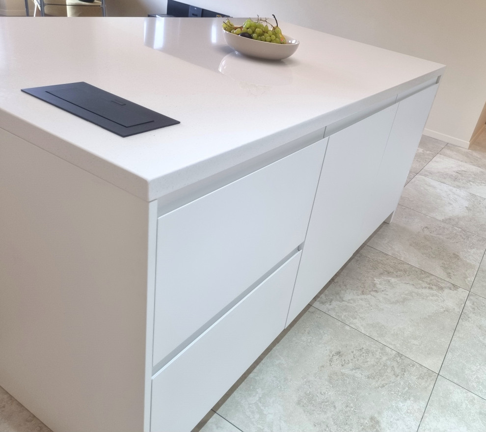 Photo of a mid-sized contemporary single-wall eat-in kitchen in Other with an undermount sink, white cabinets, solid surface benchtops, beige splashback, glass sheet splashback, panelled appliances and beige benchtop.
