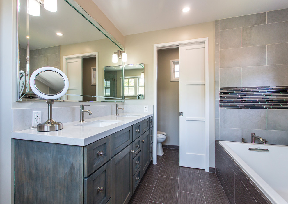 Mid-sized transitional master bathroom in Los Angeles with an undermount sink, shaker cabinets, engineered quartz benchtops, gray tile, porcelain floors, grey cabinets, a drop-in tub, porcelain tile and beige walls.