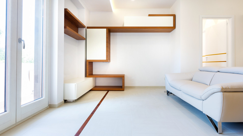 На фото: изолированная гостиная комната среднего размера в современном стиле с с книжными шкафами и полками, белыми стенами, полом из керамогранита, телевизором на стене, белым полом и акцентной стеной