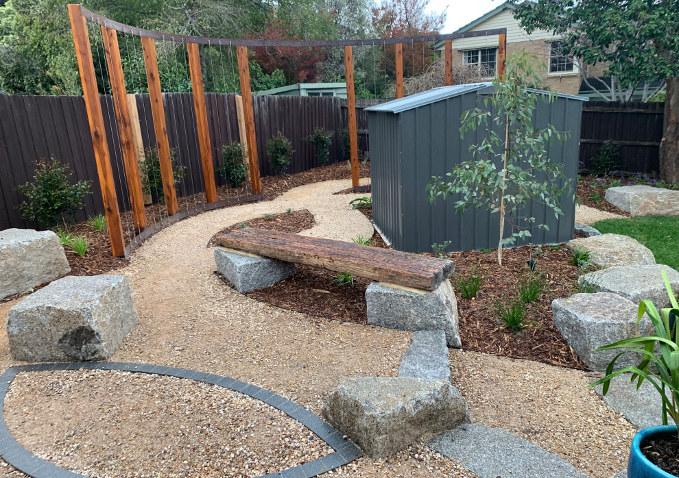 Design ideas for a mid-sized country backyard full sun xeriscape for summer in Melbourne with with rock feature and gravel.