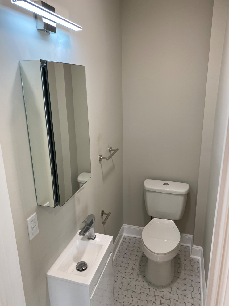 Photo of a small modern powder room in Newark with flat-panel cabinets, white cabinets, a one-piece toilet, beige walls, porcelain floors, a wall-mount sink, multi-coloured floor, white benchtops and a floating vanity.