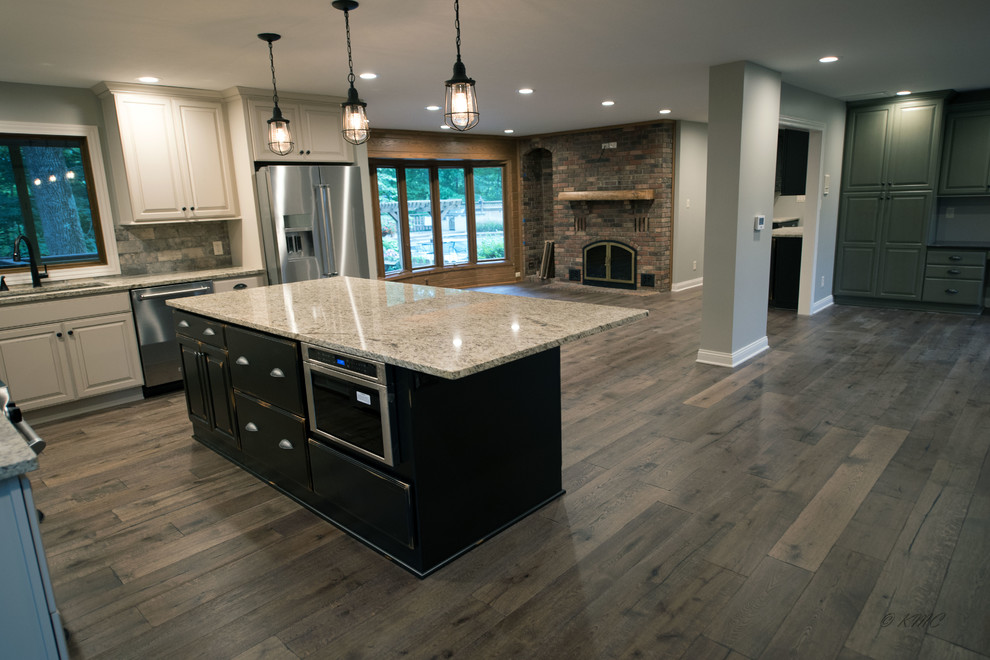 Example of a large transitional l-shaped medium tone wood floor and brown floor eat-in kitchen design in Indianapolis with an undermount sink, raised-panel cabinets, white cabinets, granite countertops, multicolored backsplash, porcelain backsplash, stainless steel appliances and an island