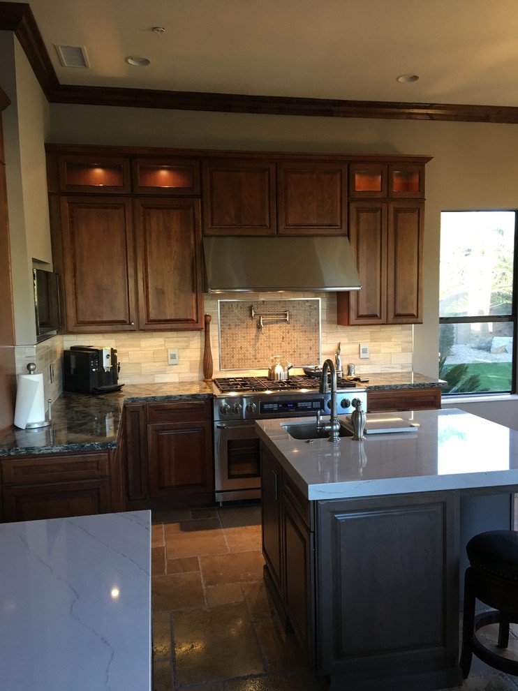 Large elegant l-shaped travertine floor eat-in kitchen photo in Phoenix with an undermount sink, raised-panel cabinets, dark wood cabinets, granite countertops, multicolored backsplash, subway tile backsplash, stainless steel appliances and an island