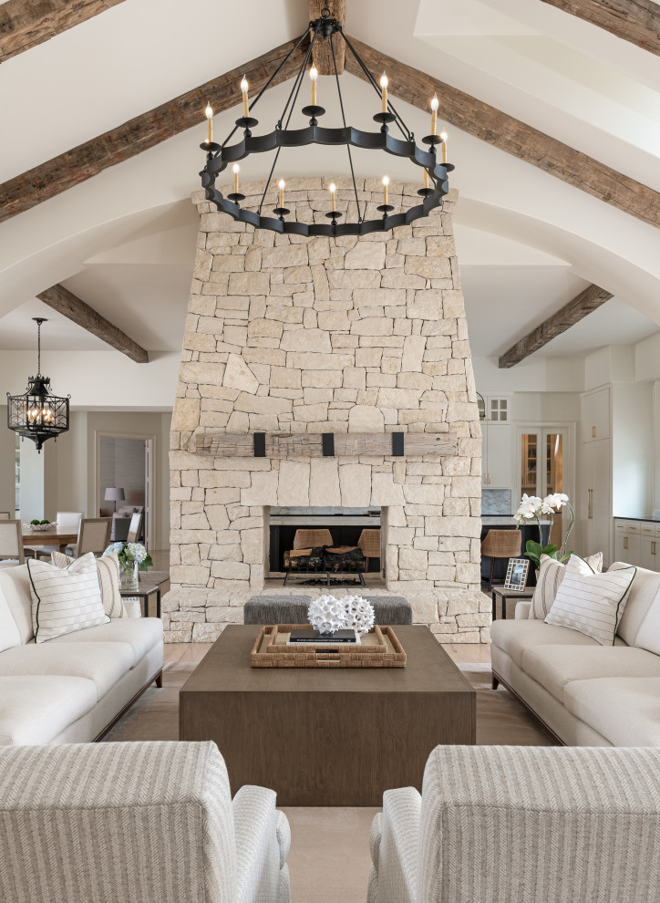 Photo of an expansive transitional open concept living room in Minneapolis with white walls, light hardwood floors, a two-sided fireplace and exposed beam.
