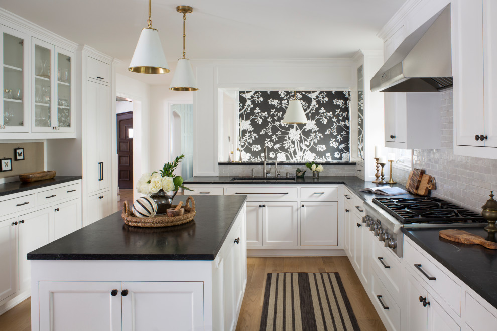 Inspiration for a contemporary u-shaped eat-in kitchen in Los Angeles with an undermount sink, recessed-panel cabinets, white cabinets, soapstone benchtops, grey splashback, subway tile splashback, panelled appliances, light hardwood floors, with island, beige floor and black benchtop.