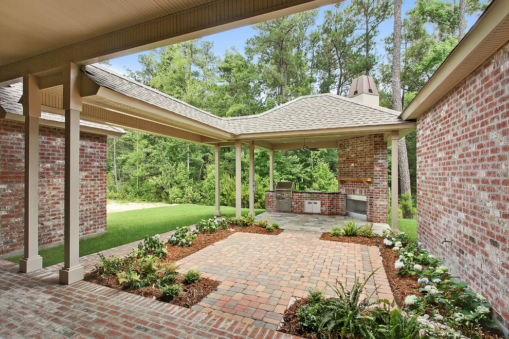 This is an example of a traditional backyard verandah in New Orleans with an outdoor kitchen, brick pavers and a roof extension.