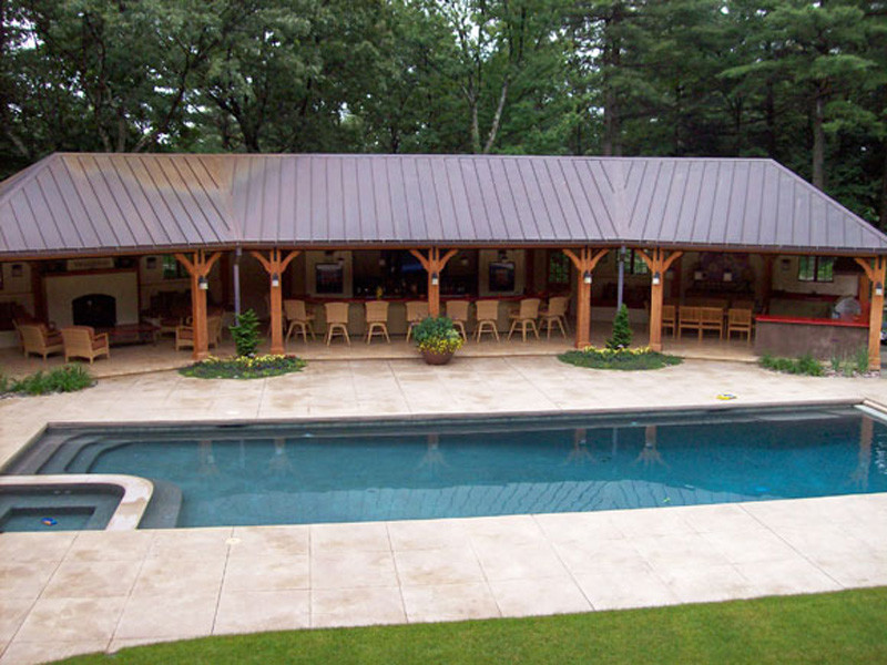 This is an example of a large country backyard rectangular lap pool in Boston with a hot tub and tile.