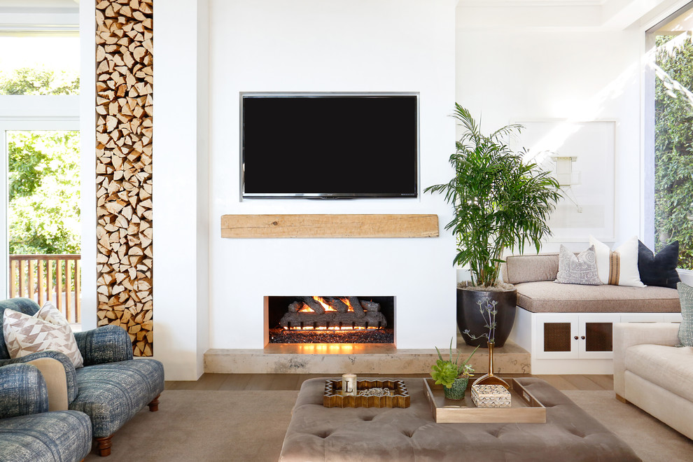 Photo of a large beach style open concept family room in Orange County with white walls, a ribbon fireplace, a plaster fireplace surround, light hardwood floors and a wall-mounted tv.