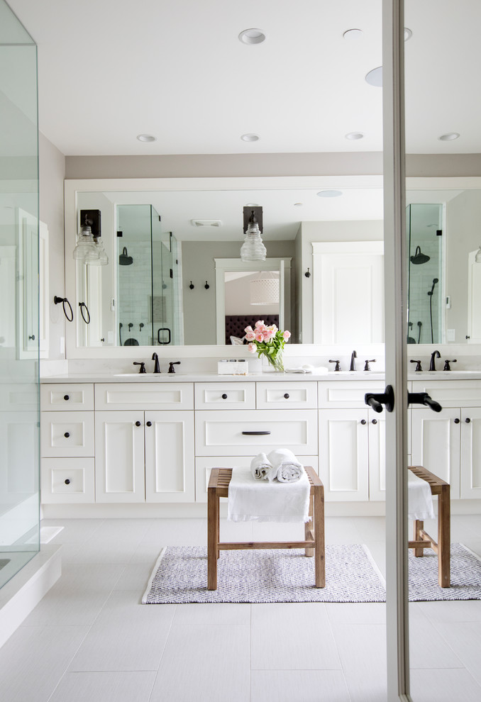 This is an example of a transitional master bathroom in Other with white cabinets, solid surface benchtops, white tile, marble, grey walls, grey floor, a hinged shower door, recessed-panel cabinets and a corner shower.