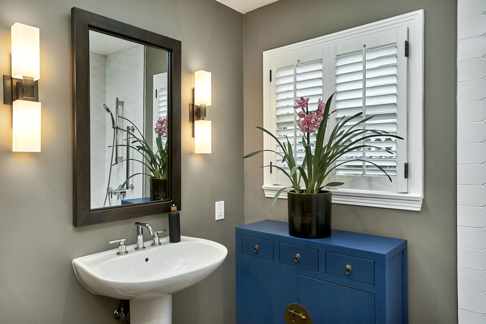 Small transitional 3/4 bathroom in San Francisco with flat-panel cabinets, blue cabinets, a corner tub, a shower/bathtub combo, a one-piece toilet, white tile, ceramic tile, grey walls, light hardwood floors, a pedestal sink, yellow floor, an open shower and white benchtops.