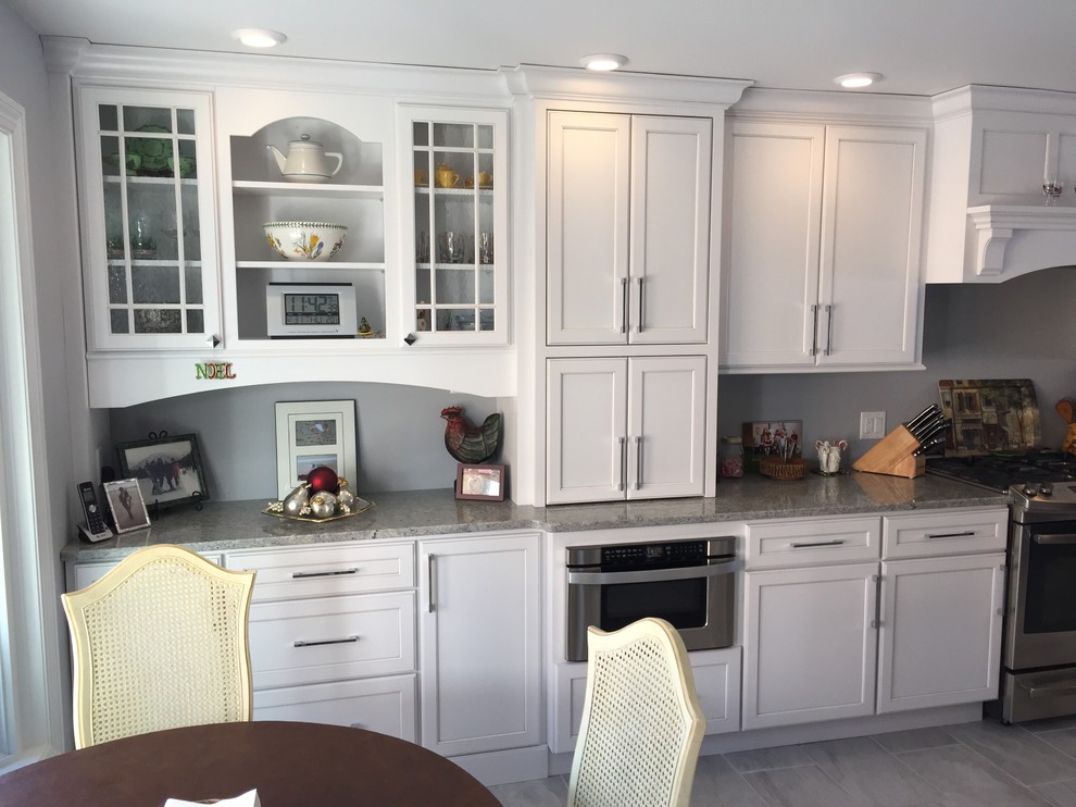 Example of a large transitional l-shaped porcelain tile and gray floor eat-in kitchen design with an undermount sink, shaker cabinets, white cabinets, granite countertops, stainless steel appliances and no island